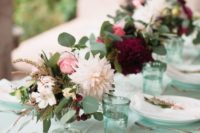 a chic and fresh wedding tablescape with a mint-colored table and glasses, bright floral centerpieces and neutral plates