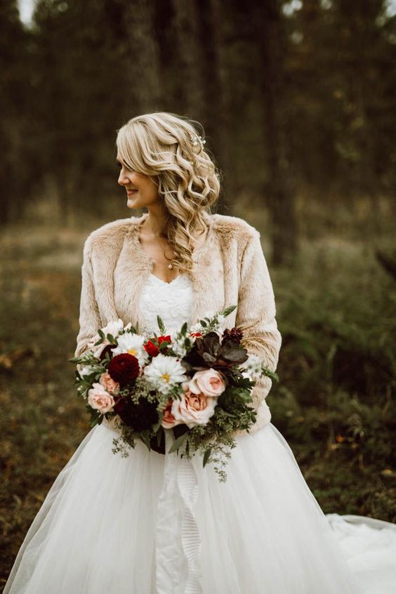 a chic and refined winter bridal look with a strapless wedding ballgown with a lace bodice and a neutral faux fur cover up is cool