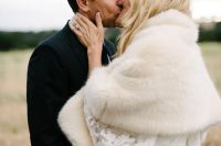 a chic lace fitting wedding dress with bell sleeves paired up with a neutral faux fur cover up for a modern romantic bridal look