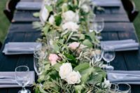 a dark stained table softened with a lush greenery and pink and white blooms table runner