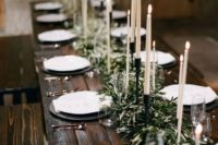 a dark stained table with olive branches and tall candles looks very refined and chic