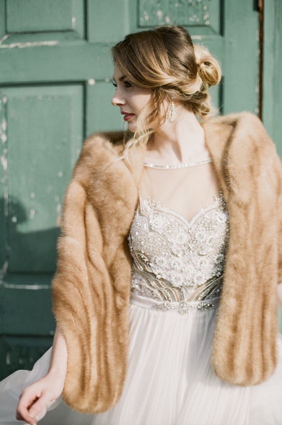 a fab winter bridal look with an embellished A-line wedding dress, statement earrings and a brown faux fur cover up is gorgeous