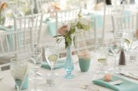 a fresh spring wedding table in white and mint blue – napkins, vases and cups with blooms