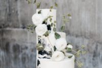 a gorgeous black and white brushstroke wedding cake decorated with white ranunculus and greenery
