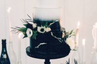 a gradient black and white wedding cake with white anemones, greenery and blush blooms is very elegant