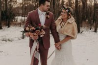 a lace mermaid wedding dress with a neutral faux fur cover up and a floral crown for a boho-inspired winter wedding