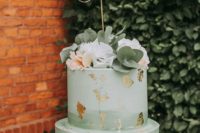 a lovely mint green brushstroke wedding cake with gold leaf and fresh blooms and greenery for a wedding