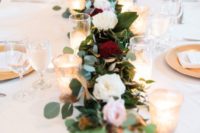 a lush floral table runner with candles will visually elongate the tables and make them bolder