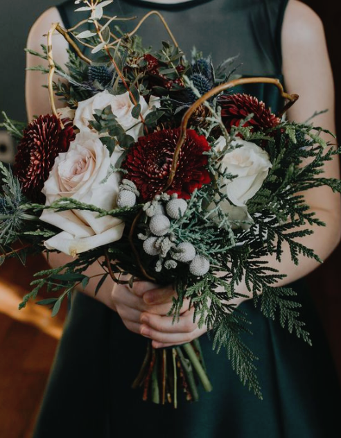 a lush winter wedding bouquet with red and blush blooms, thistles, vine, ferns and berries