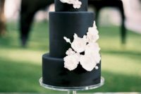 a matte black wedding cake with white sugar flowers is a stylsh and timeless idea that works