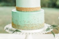a mint-colored wedding cake with gold glitter, blush and white roses is very glam and elegant