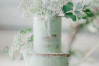 a mint semi naked wedding cake with baby’s breath, greenery and a sugar topper