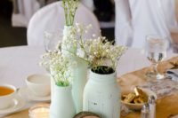 a mint wedding centerpiece composed of jars and bottles, baby’s breath and candles