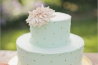 a pretty mint wedding cake with gold dots, with a pink bloom on top looks romantic