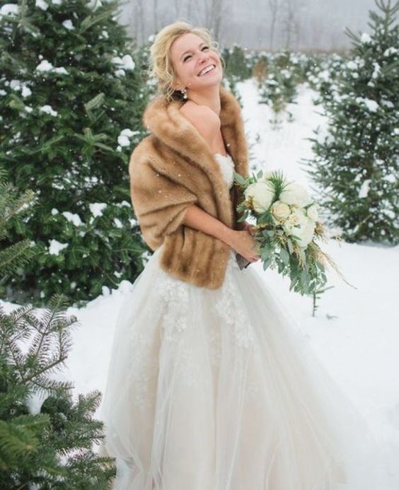 a refined lace strapless wedding ballgown with a beige faux fur stole are a great combo for a sophisticated winter bride