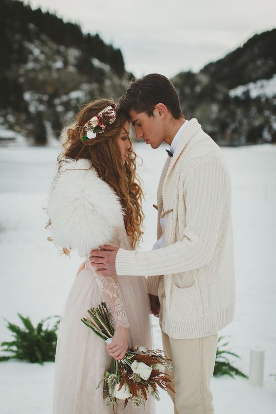 a romantic winter bridal look with a neutral A-line wedding dress of lace and a white faux fur cover up plus a floral crown
