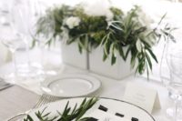 a simple modern tablescape with striped black and white napkins, much greenery and a neutral tablecloth