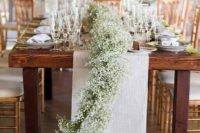 a striped fabric table runner and a baby’s breath one combined for a refined rustic touch