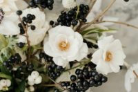 a white bloom wedding bouquet with black berries and touches of greenery is a chic casual idea