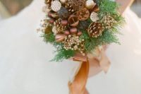 a woodsy-inspired bouquet with gilded pinecones, ornaments, berries, nuts, fern and a camel ribbon