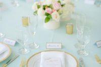 an elegant wedding table with a mint tablecloth, gold touches and a neutral and pink floral centerpiece is chic