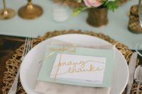an elegant wedding tablescape with a mint table runner and a card plus touches of gold and brass
