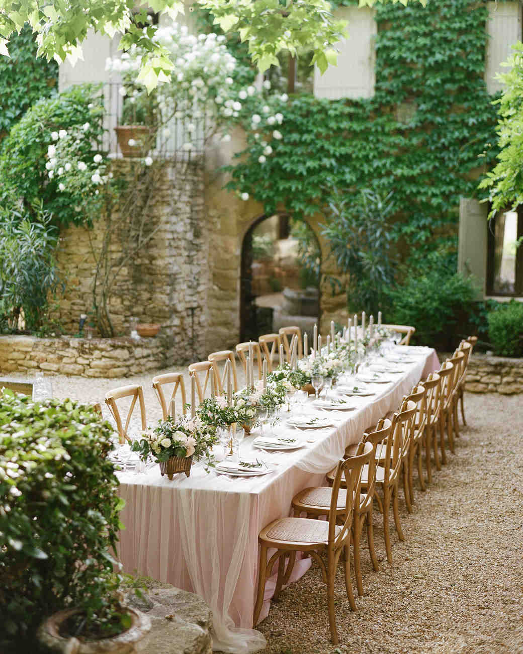 Blush tablecloths and tulle overlays, blush flower and greenery centerpieces for these long tables