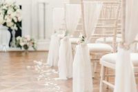 ethereal wedding chair decor with white fabric, white blooms and greenery and petals on the floor is amazing