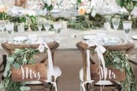 greenery, wooden plaques, white ribbon bows for chic and stylish wedding chair decor with a strong rustic feel