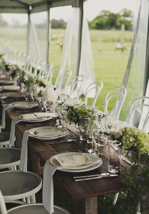long uncovered tables decorated with greeneyr and white bloom centerpieces for a chic modern look