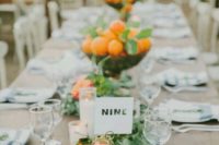 lush greenery and orange blooms plus peach centerpieces in bowls and simple table numbers