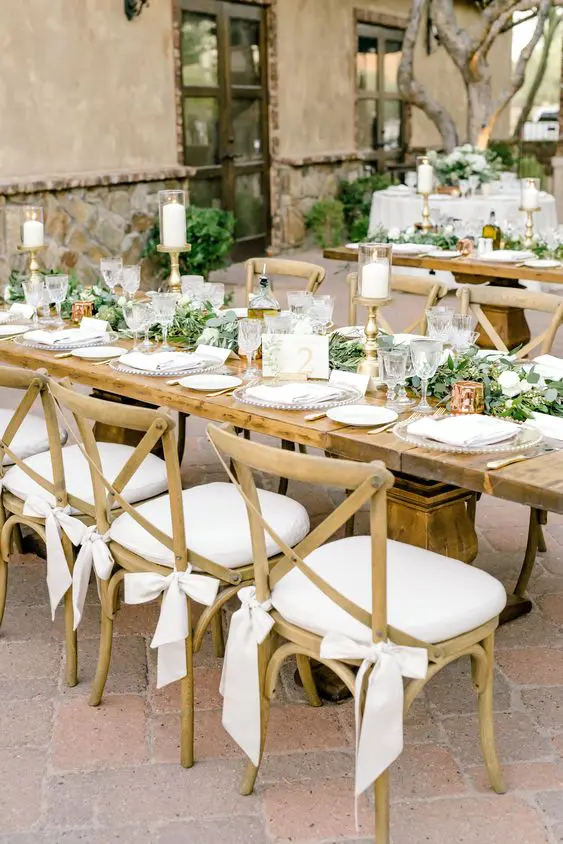stained chairs with white seats and white ribbon bows are an elegant and chic idea for a farmhouse wedding or a countryside one but with an elegant feel