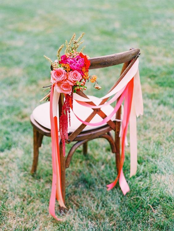super bright red and pink ribbons and a colorful floral posie with greenery and berries are amazing for wedding chair decor, for a wedding with plenty of color
