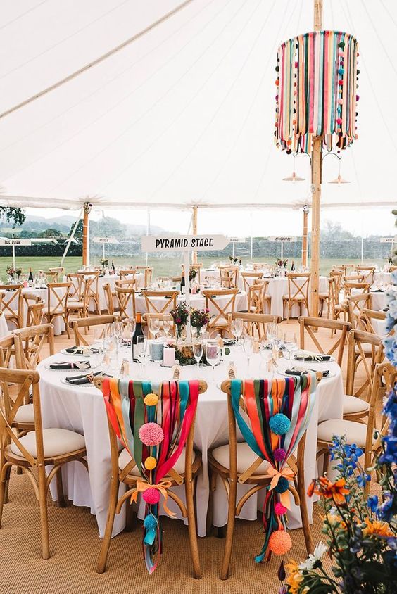 super colorful wedding chair decor with bright ribbons, large colorful pompoms and orange bows is amazing for a bright festival wedding