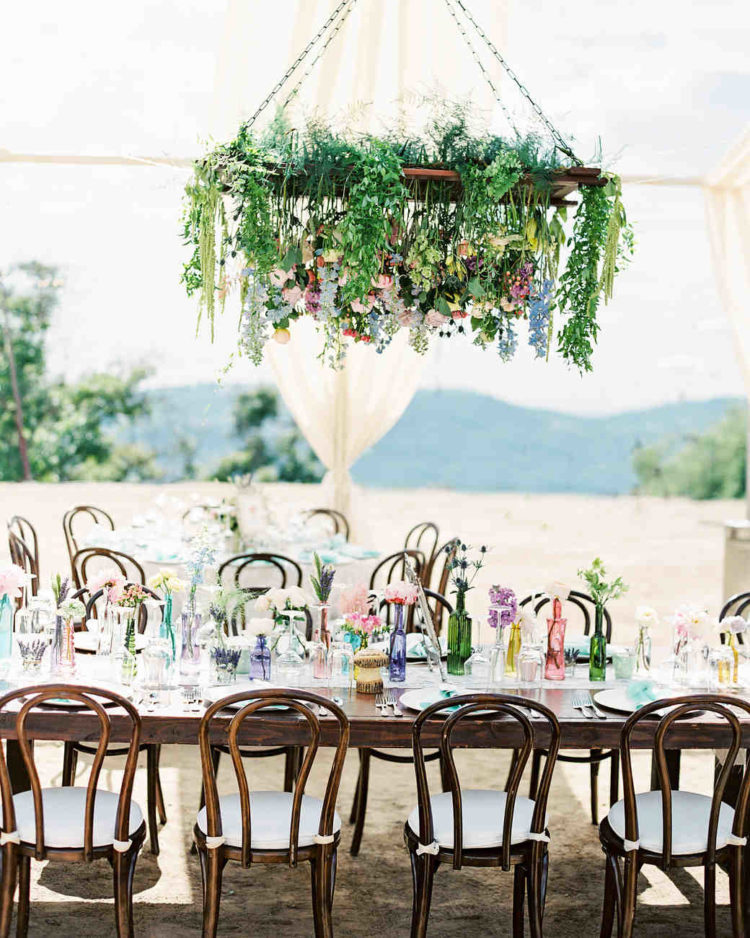 the colorful glass bottles on this dreamy tablescape were matched perfectly to the flowers hanging above
