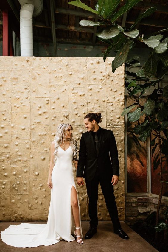 the groom in a total black outfit, the bride wearing a total white outfit with a minimalist feel