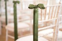 white chairs accented with green silk ribbons and bows in a very chic and elegant way to give them a spring-summer feel