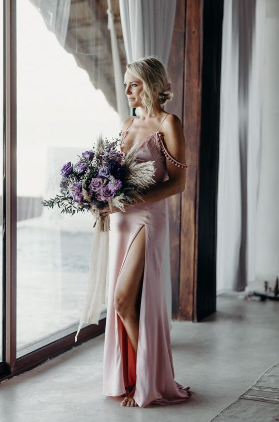 Malin Akerman wearing a pink silk spaghetti strap wedding dress with pompom detailing and a front slit for a modern and boho feel