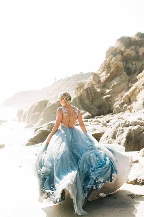 a beautiful coastal wedding dress with a white lace bodice and an illusion back, a blue layered skirt with a train is a chic idea
