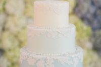 a blue and white wedding cake decorated with lace flowers and edible beads is very cute and ideal for spring or summer