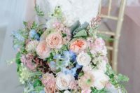 a blush, peachy and blue wedding bouquet with much greenery and some neutral blooms