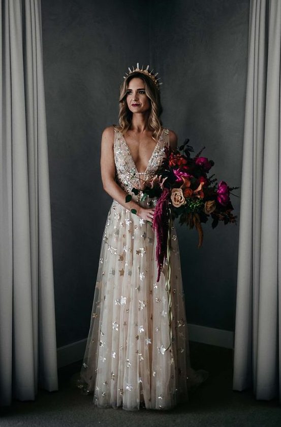 a blush thick strap wedding dress with foil stars and a plunging neckline plus a crystal crown for a celestial bride