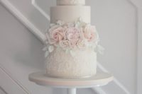 a blush wedding cake with white lace patterns, blush sugar blooms and white leaves of sugar is very tender and cute