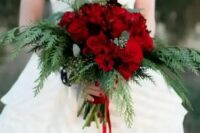 a bright and chic Christmas wedding bouquet of red roses and ferns plus red ribbons is gorgeous