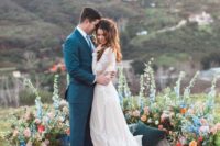 a bright boho wedding altar of colorful blooms with greenery and layered boho rugs is a cool piece