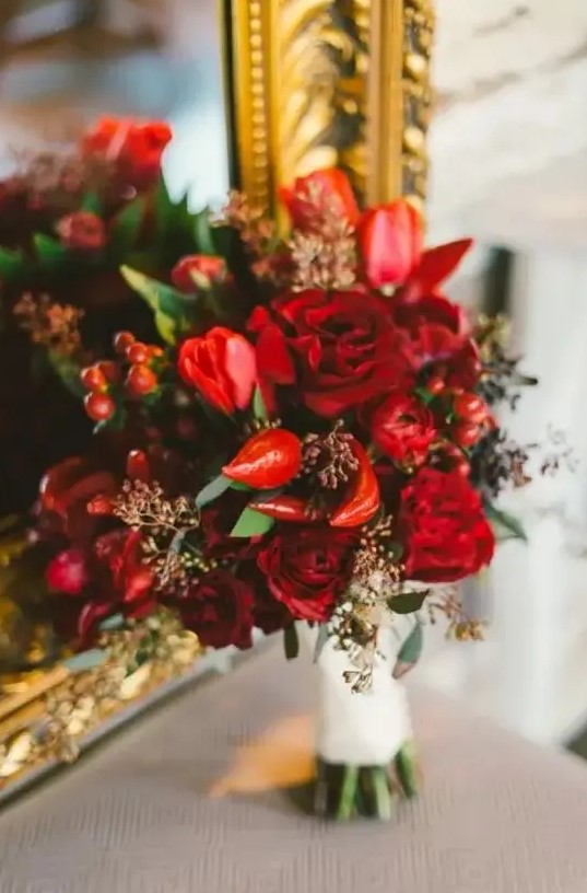a bright red and burgundy Valentine wedding bouquet with berries and peppers is all about spicy love