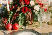 a bright wedding tablescape with pomegranates, greenery, white and red blooms and berries on the place setting
