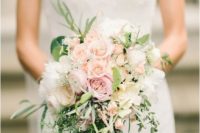 a cascading pastel wedding bouquet with blush and peachy blooms, greenery of various kinds