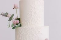 a chic white floral lace wedding cake decorated with blush blooms and greenery looks chic and modern