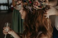 a fantastic moody flower crown with blue, red and pale rust blooms and dried leaves and herbs for a fall boho wedding